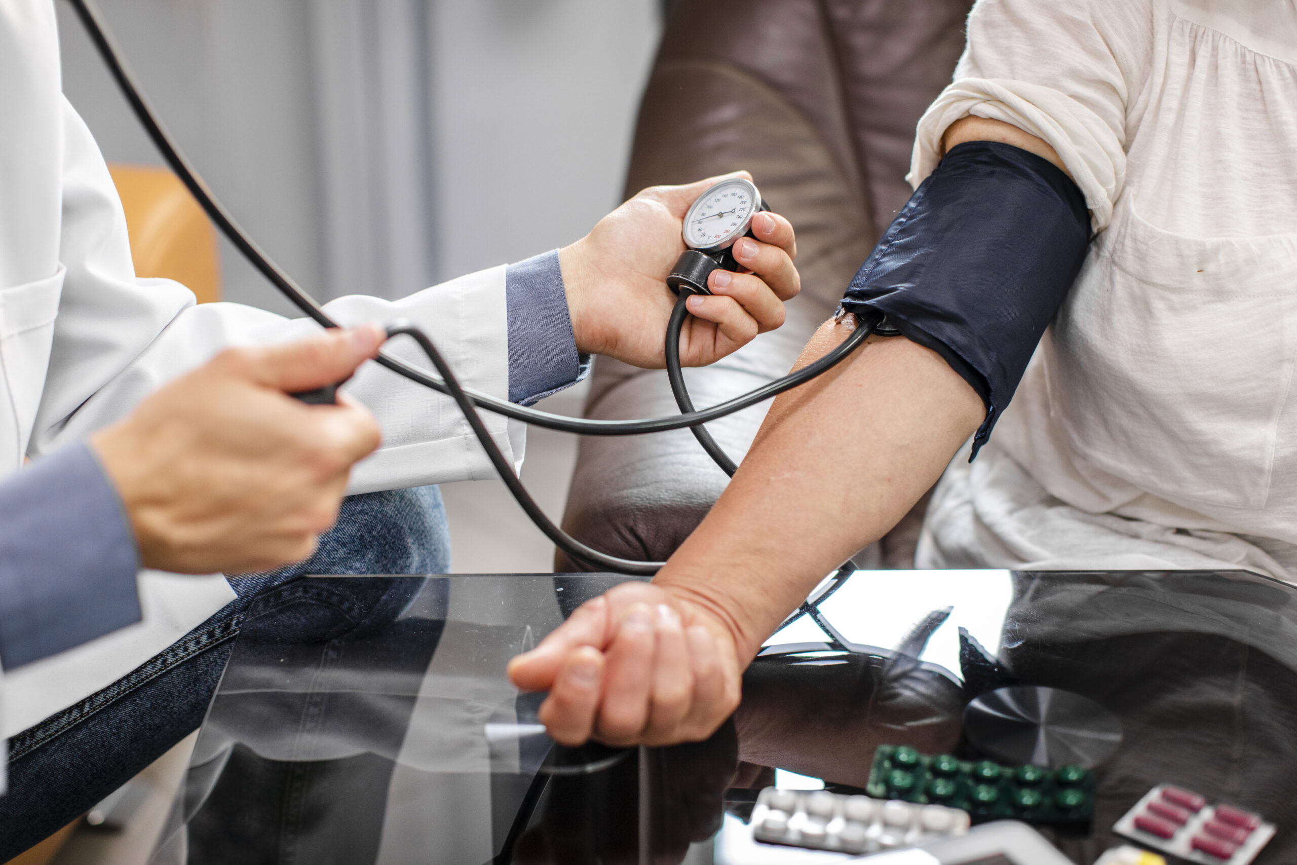 Healthcare professional measuring a patient’s blood pressure using a manual sphygmomanometer during a clinical consultation.